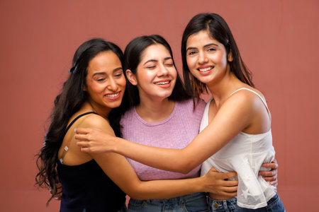 Portrait of three beautiful young women hugging each other and smiling.の写真素材