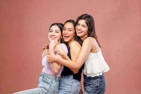 Three young women smiling and looking at camera isolated on pink backgroundの写真素材