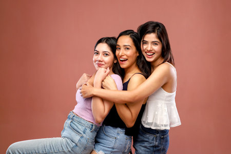 Portrait of three beautiful young women laughing and looking at the cameraの写真素材