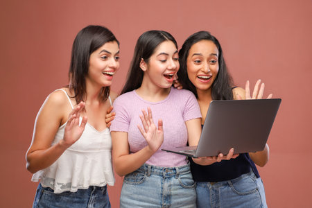 Three asian women with laptop on brown background. Concept of friendshipの写真素材