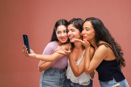 Portrait of three young women taking a selfie with a mobile phoneの写真素材