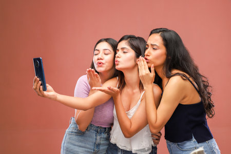 Three young asian women taking a selfie with a mobile phone.の写真素材