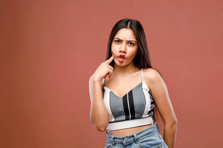 Portrait of a beautiful young woman making a funny face on brown backgroundの写真素材