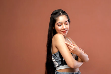 Young beautiful asian woman in sportswear posing on brown backgroundの写真素材