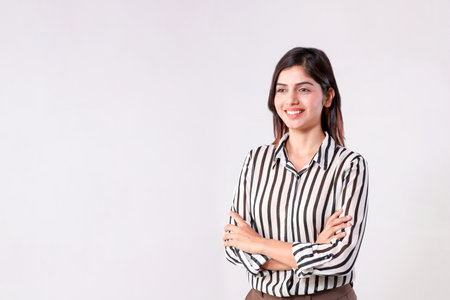 Portrait of a happy young businesswoman standing with arms crossed against white backgroundの写真素材