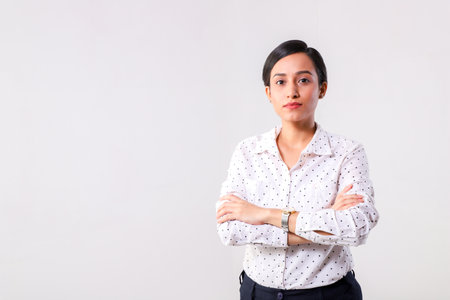 Portrait of a young businesswoman standing with arms crossed against white backgroundの写真素材