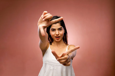 Portrait of a beautiful young woman making a frame with her handsの写真素材