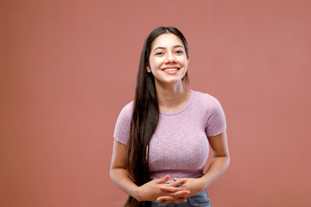 Portrait of a smiling young woman with long hair on pink backgroundの写真素材