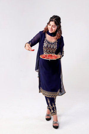 Young indian woman in saree holding a plate of food.の写真素材