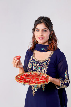 Beautiful young Indian woman in sari holding plate with candlesの写真素材