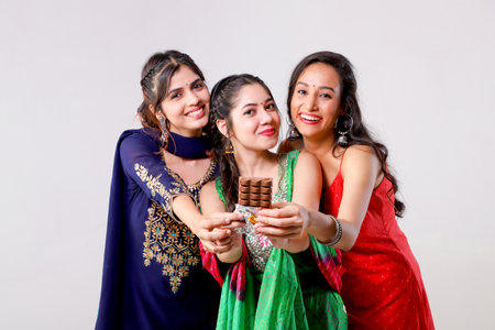Group of indian young women eating chocolates in the studioの写真素材