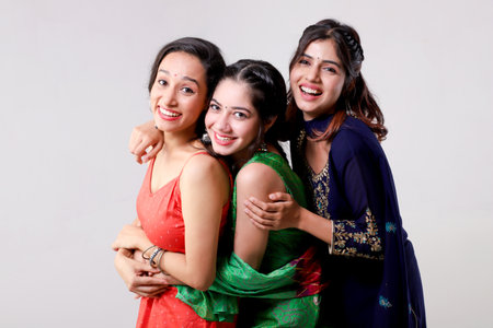 Three young indian women in saree standing and hugging each otherの写真素材