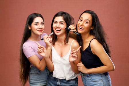 Portrait of three young women looking at camera and smiling while applying makeupの写真素材
