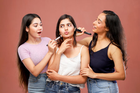 Three young women having fun while applying make up with a brush.の写真素材