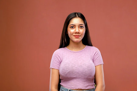Portrait of a beautiful young woman smiling against brown backgroundの写真素材