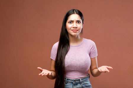 Portrait of a young woman shrugging shoulders on brown backgroundの写真素材