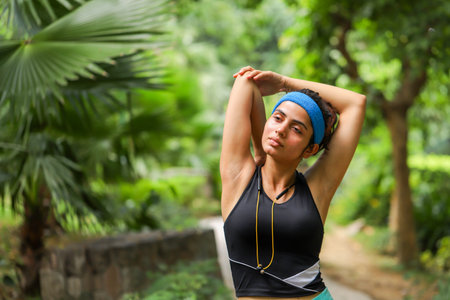Portrait of young woman doing stretching exercise in the park at daytimeの写真素材