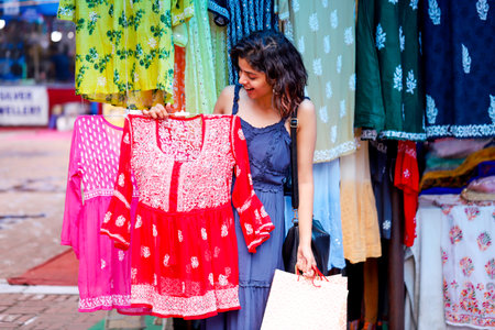 Shopping in the market. A young woman is buying clothes.の写真素材