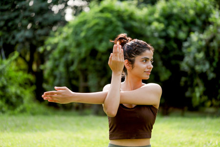 Young woman practicing yoga in the park. She is looking at the camera and smilingの写真素材