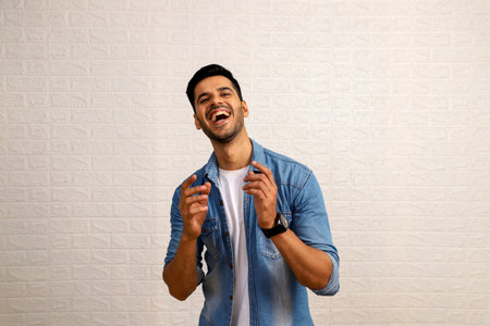 Portrait of a young man laughing against a white wall background.の写真素材