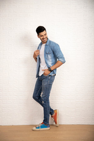 Full length portrait of a happy young man standing against a white wallの写真素材