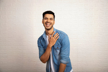 Portrait of a happy young man laughing on a white wall backgroundの写真素材