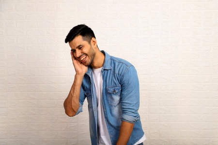 Portrait of a happy young man laughing on white wall background.の写真素材