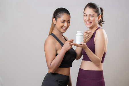 Portrait of two happy Asian women in sportswear with bottle of protein shakeの写真素材