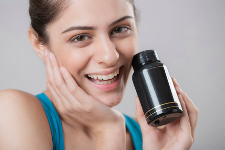 Portrait of a smiling young woman holding a bottleの写真素材