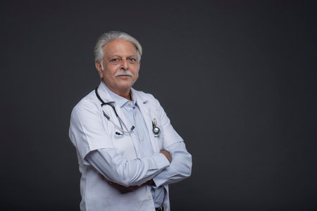 Portrait of a senior doctor with stethoscope on grey backgroundの写真素材