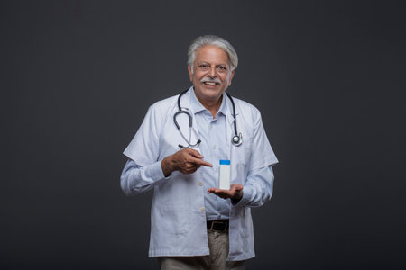 Portrait of senior asian doctor with stethoscope and bottle of medicineの写真素材