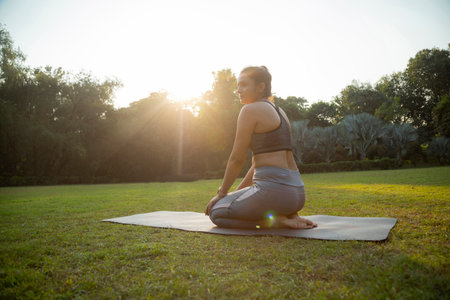 Side view of woman practicing yoga in the park on a sunny dayの写真素材