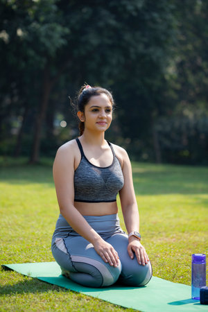 Young woman doing yoga exercise in the park. Healthy lifestyle concept.の写真素材