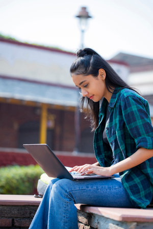 Young woman using laptop in the park. Education and technology concept.の写真素材