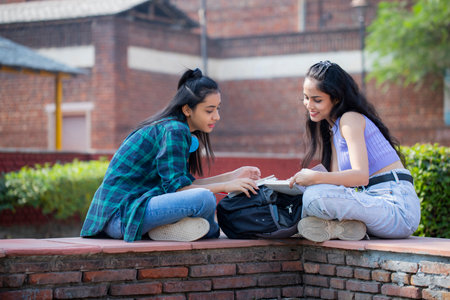 two asian teen high school students studying and reading a book outdoorの写真素材