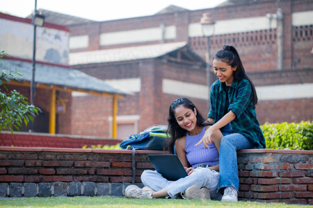 Portrait of a smiling female student sitting on campus with her friendの写真素材