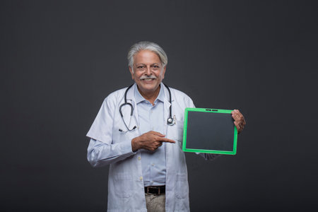 Portrait of senior doctor holding a tablet computer and pointing at itの写真素材