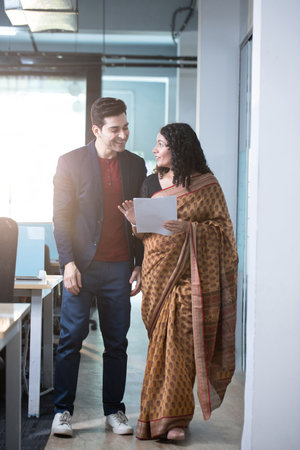 Portrait of businessman and businesswoman discussing over document while standing in officeの写真素材