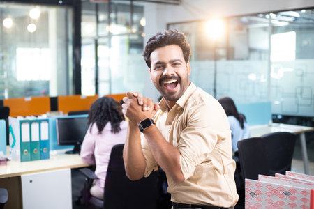 Portrait of happy businessman with arms crossed while colleague standing in officeの写真素材