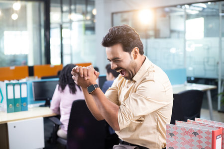 Portrait of happy businessman using smartwatch while colleagues working in office