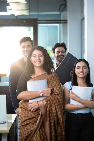 Portrait of smiling business team standing in office with colleagues in background