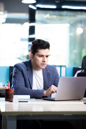 Portrait of young businessman working on laptop computer at office desk.の写真素材