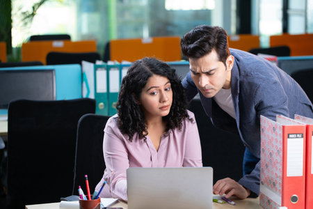 Portrait of two young businesspeople working together at desk in office