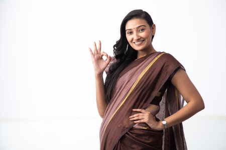 indian woman wearing sari showing ok hand sign on white background