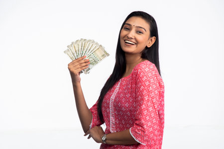 Young woman in pink suit and showing currency notes on white background