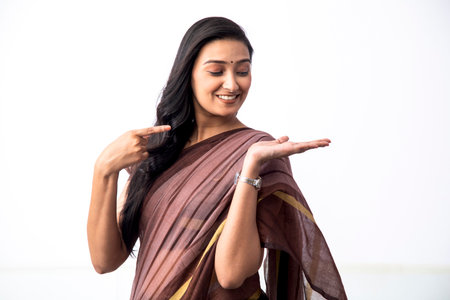 Portrait of a woman standing over white background while presenting with hand and pointing with her fingerの写真素材