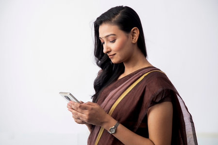 Portrait of a beautiful Indian woman using mobile phone on white backgroundの写真素材