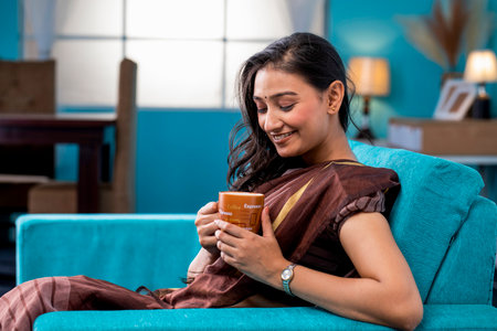 Beautiful woman sitting on a sofa with a cup of coffeeの写真素材