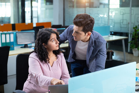 Portrait of two businesspeople working together at desk in creative office