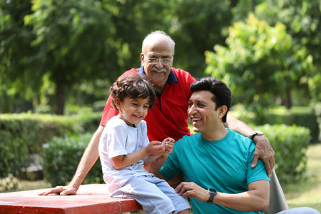Grandfather and grandson sitting on bench in park at summer